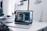 A MacBook with lines of code on its screen on a busy desk