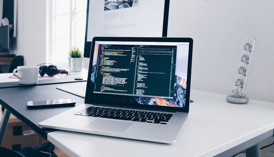 A MacBook with lines of code on its screen on a busy desk