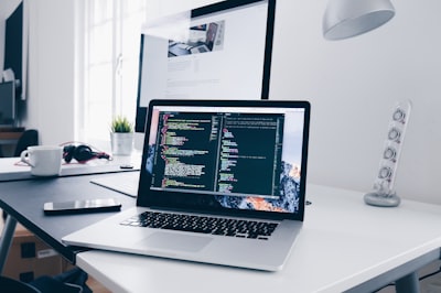 Pozycjonowanie stron internetowych - A MacBook with lines of code on its screen on a busy desk