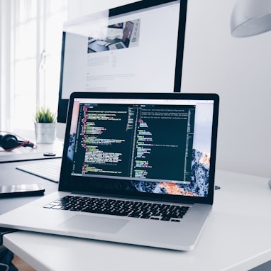 A MacBook with lines of code on its screen on a busy desk