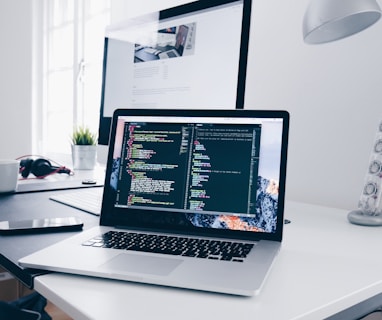 A MacBook with lines of code on its screen on a busy desk