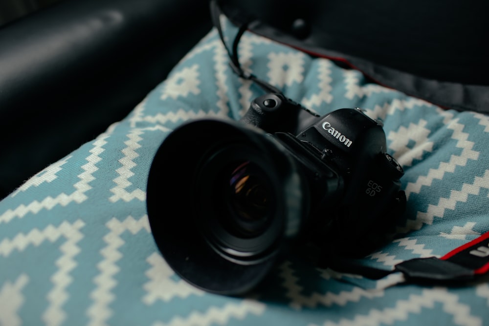 schwarze Canon DSLR-Kamera auf blau-weißem Kissen
