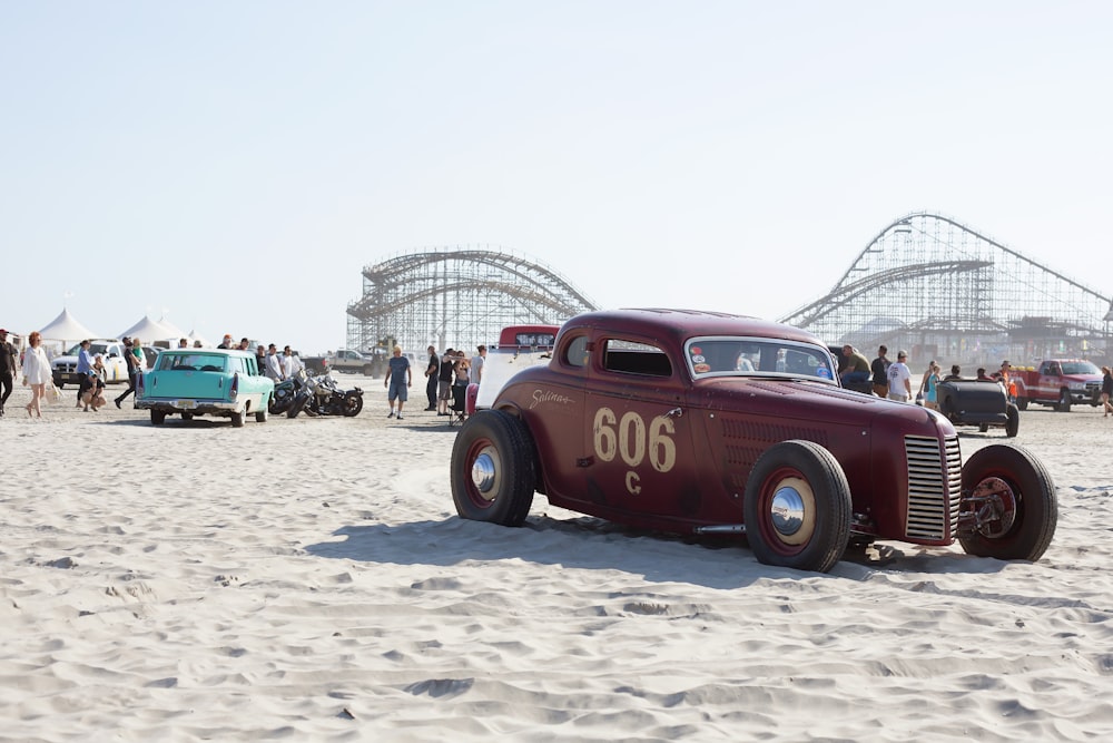 red and black vintage car on white sand during daytime