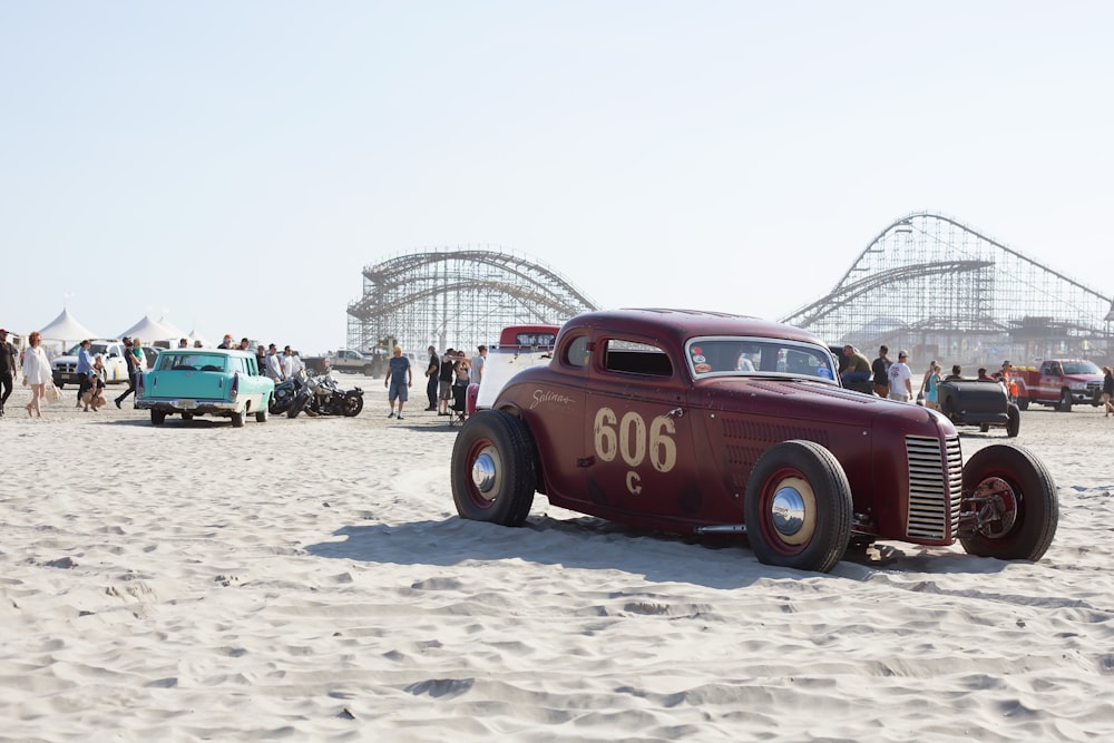 Roter und schwarzer Oldtimer auf weißem Sand während des Tages