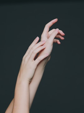 Two hands holding intertwined threads against a backdrop of zodiac symbols.