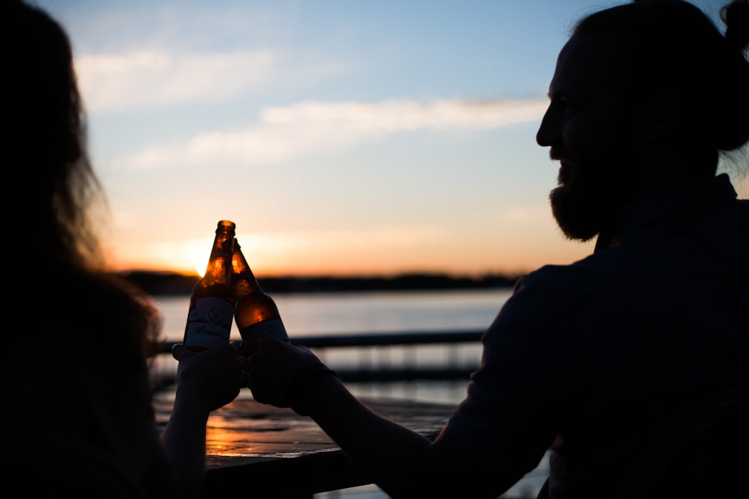 silhouette photography of man and woman carrying beer bottles, Cheers