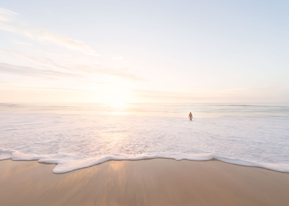 Persona che nuota nell'oceano durante il tramonto