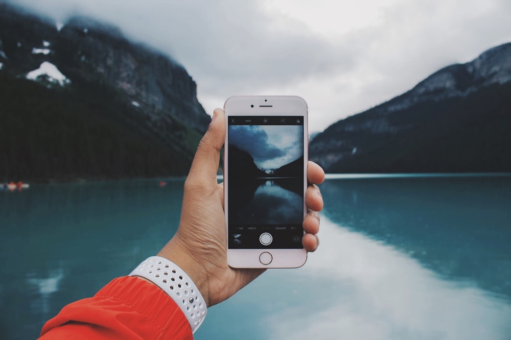 person taking photo of lake