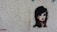 A stylized stencil painting of a woman's face with prominent black hair and red accents on a textured, light-colored wall. The artwork captures a mysterious and bold expression.