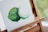 An abstract painting of two overlapping circular shapes with a textured finish, displayed on a wooden easel. The painting primarily uses shades of green and white, with visible brushstrokes creating a sense of depth.