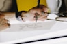 person lettering on tracing paper using mechanical pencil