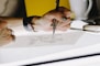person lettering on tracing paper using mechanical pencil