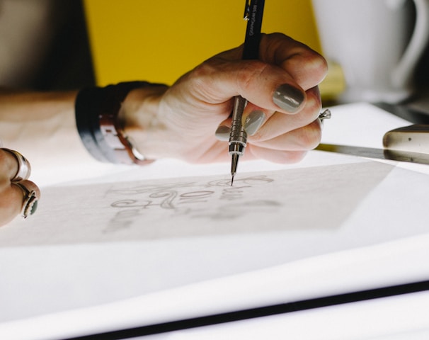 person lettering on tracing paper using mechanical pencil