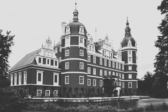 A grand medieval noble residence surrounded by lush gardens and tall stone towers.