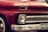 A close-up view of the front of a vintage red Chevrolet vehicle, featuring a classic design with prominent headlights, chrome detailing, and a visible license plate with the number FKKI03C. The paint is glossy, reflecting the surroundings, and the car's brand name is displayed on the grille.