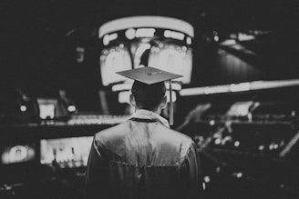Black and white image of a graduate with cap, looking towards the future at a crossroads