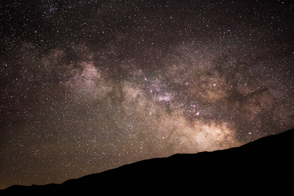 silhouette of hill under starry sky