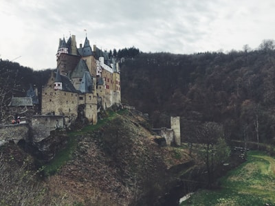 A stark black and white photo of a solitary castle perched on a misty hill.