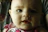Close-up of a happy baby chewing on a pastel-colored teething ring with soft natural light