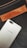 A gray smartphone with the UMIDIGI logo is positioned diagonally over a black fabric background. Above the phone, a brown leather patch with the word 'DIESEL' embossed on it is seen, along with a zipper detail.