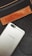 A gray smartphone with the UMIDIGI logo is positioned diagonally over a black fabric background. Above the phone, a brown leather patch with the word 'DIESEL' embossed on it is seen, along with a zipper detail.