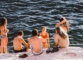 group of kids having a conversation near body of water