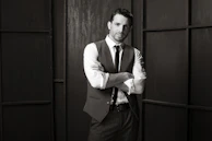 Editorial-style portrait of a bearded man adjusting his collar, exuding quiet confidence.