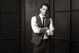 A sleek, dark-themed portrait of a confident man dressed in elegant modern attire, embodying refined masculinity.
