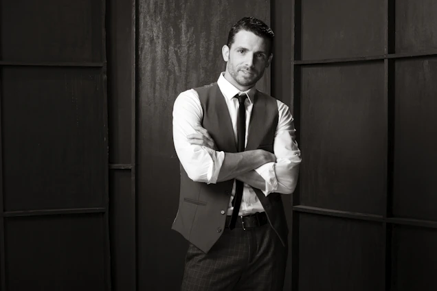 A sleek, dark-themed portrait of a confident man dressed in elegant modern attire, embodying refined masculinity.
