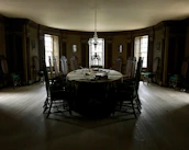 Classic dining table with ornate carvings set in a warmly lit room.