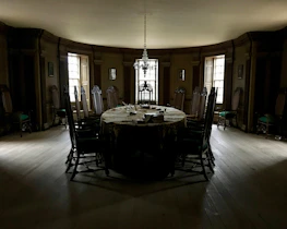 Classic dining table with ornate carvings set in a warmly lit room.