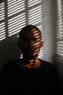 A calm, focused person in a dimly lit room, symbolizing clarity and resilience.