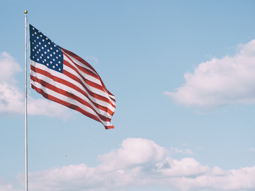 bandeira dos E.U.A. sob nuvens brancas durante o dia