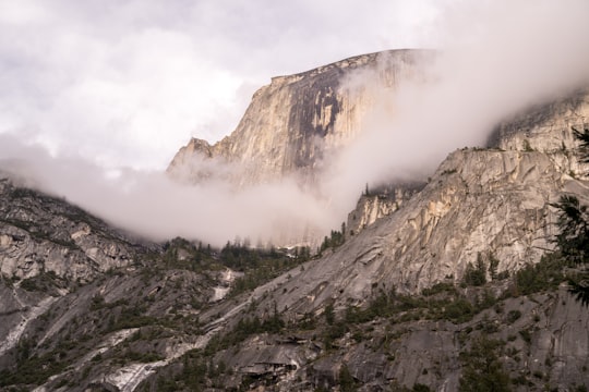 mountain covered by clouds and surrounded by trees in Yosemite National Park, Half Dome United States