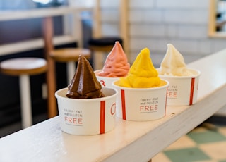 four assorted flavor of ice cream on white wooden table