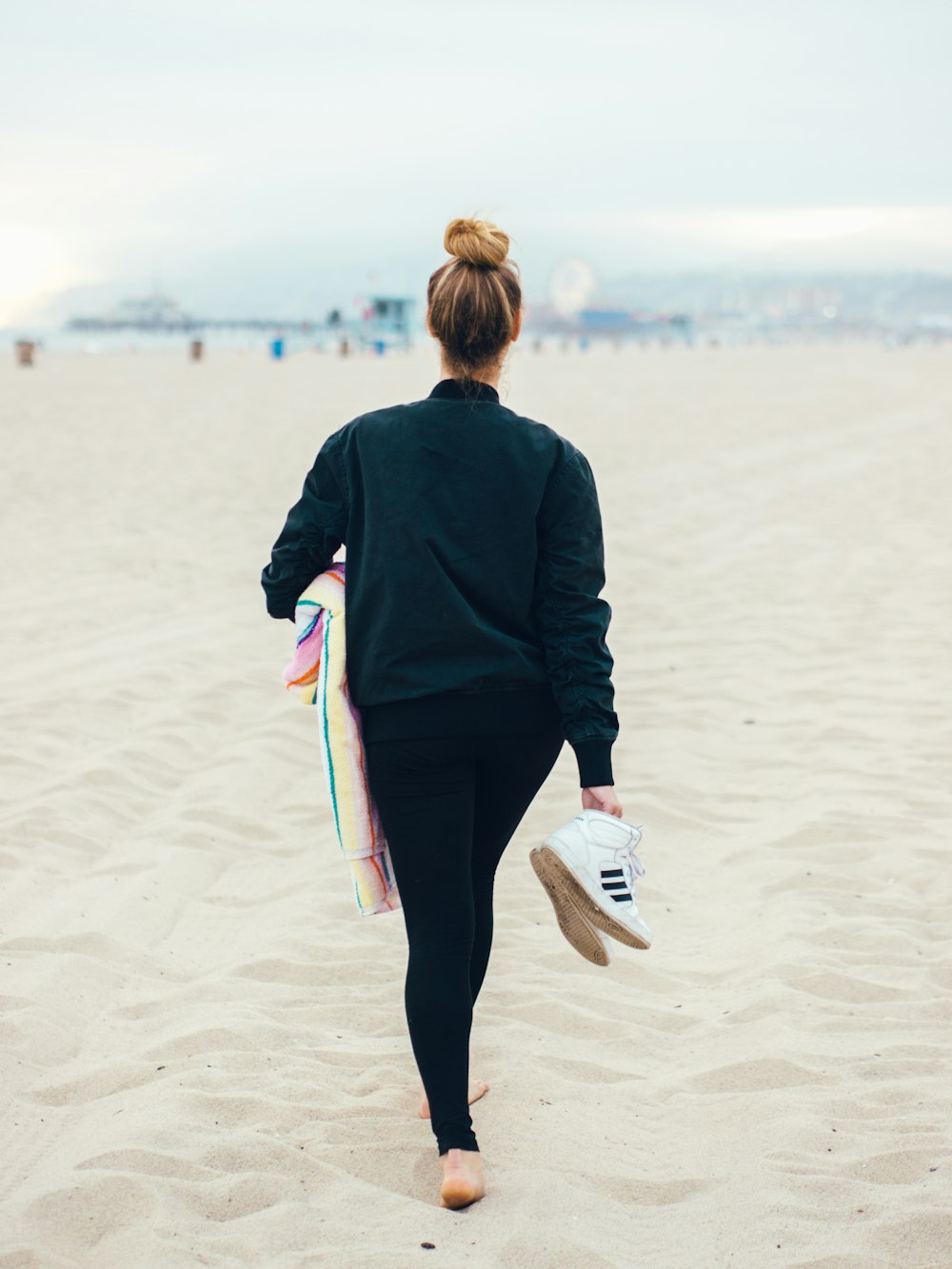 woman carrying pair of white Adidas shoes