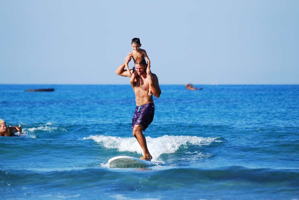 man surfing carrying boy