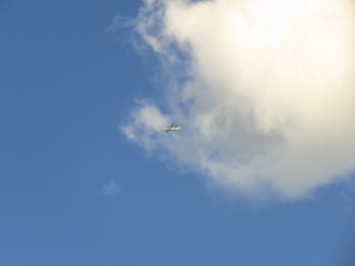 An elegant airplane soaring above fluffy clouds against a deep blue sky, symbolizing smooth travel.