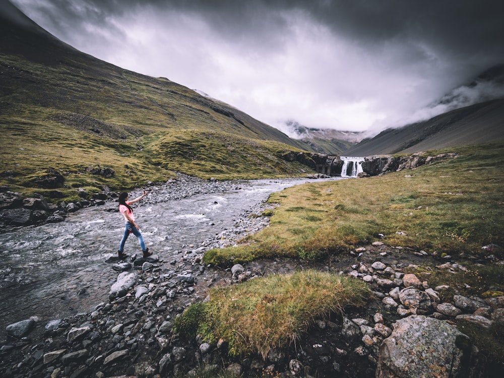 femme en jeans bleu traversant la rivière