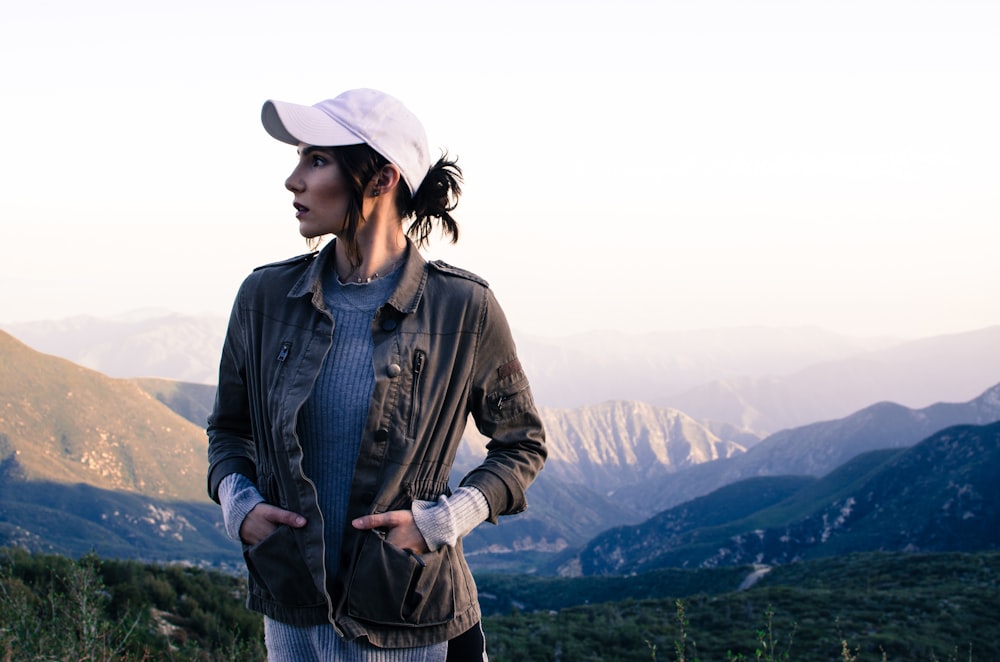mulher na jaqueta marrom em pé no topo da montanha durante o dia