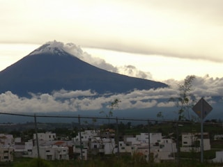 A panoramic view of a snow-covered volcano towering over a quiet village.
