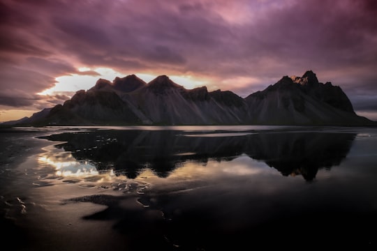 mountains reflecting on body of water in Höfn Iceland