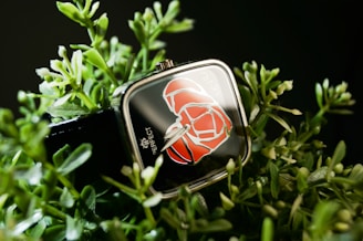 An intricate miniature garden scene with colorful flowers and a small bench, all inside a square watch case.