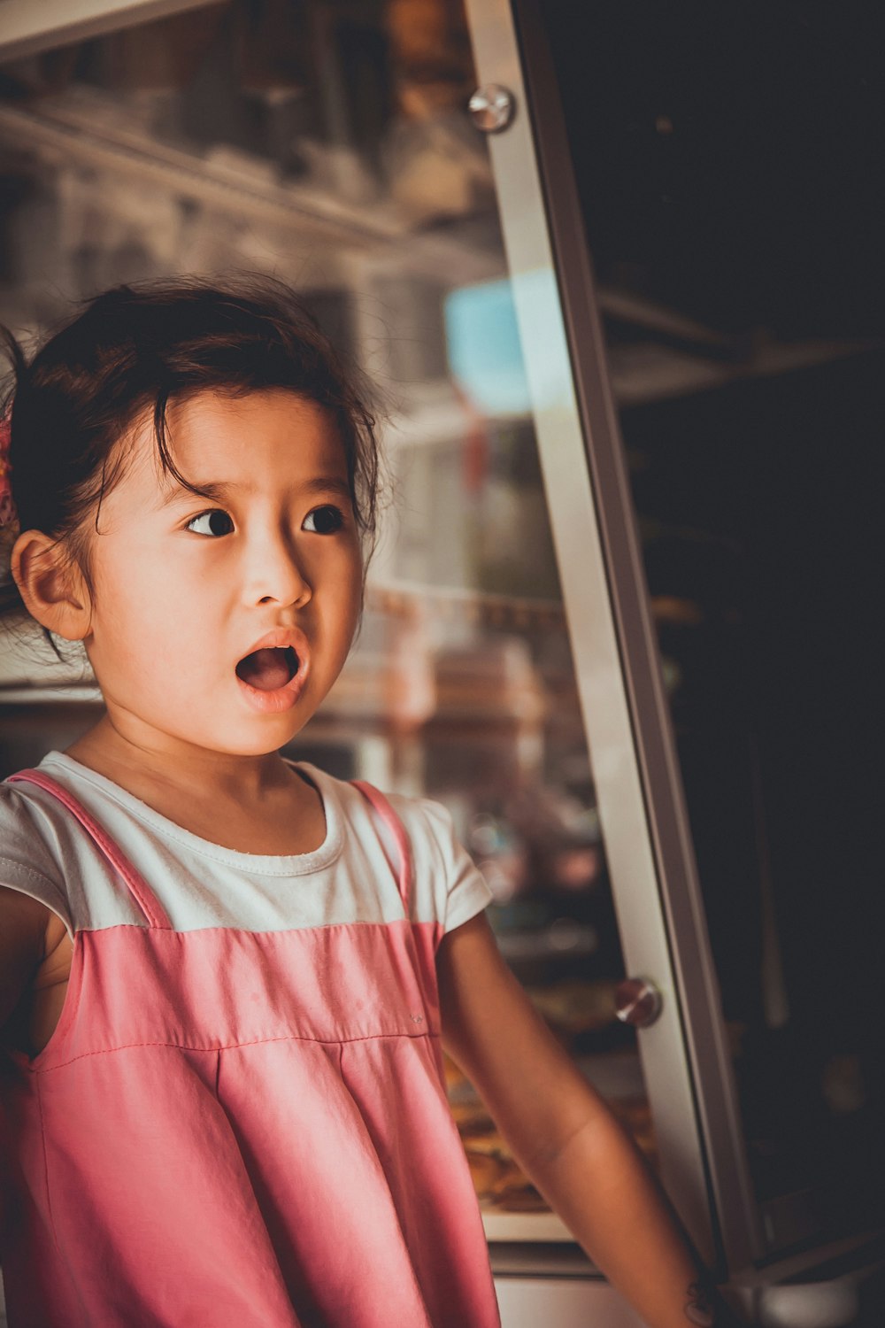 menina que está ao lado da janela de vidro