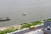 Aerial view of a cargo boat moving through a narrow inland waterway with small town buildings nearby.