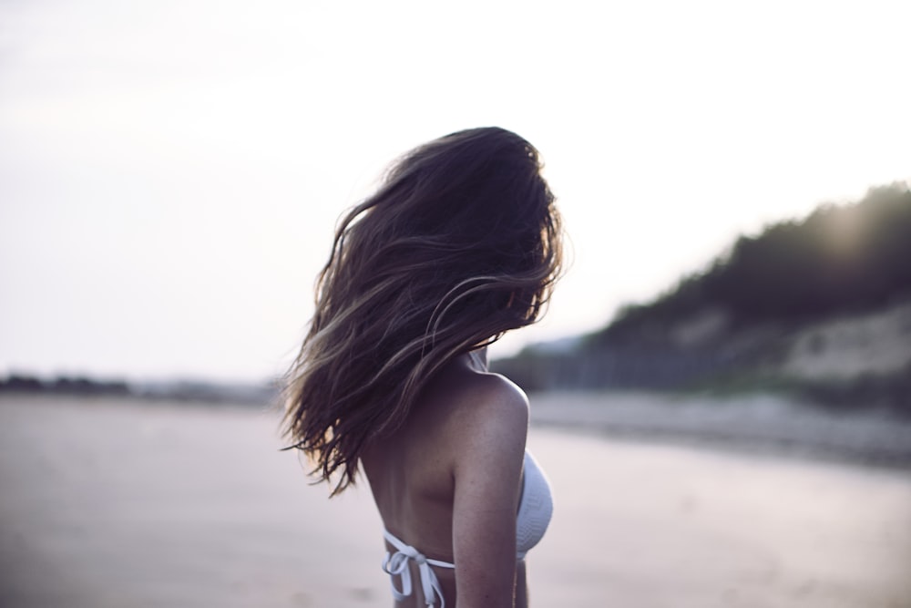 woman standing wearing white bra in selective focus photography