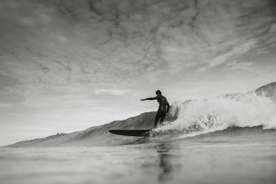 grayscale photo of person surfing under cloudy sky in Saint-Nazaire France