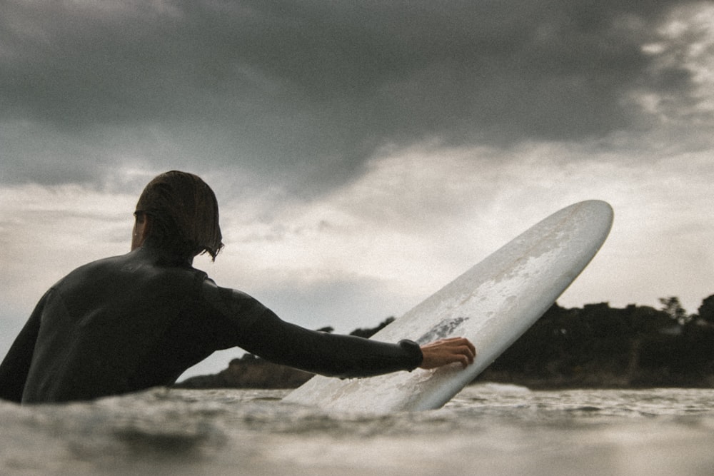 man swimming with surfboard