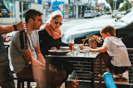 Families enjoying a sunny day sitting at outdoor tables near the mall's food court.