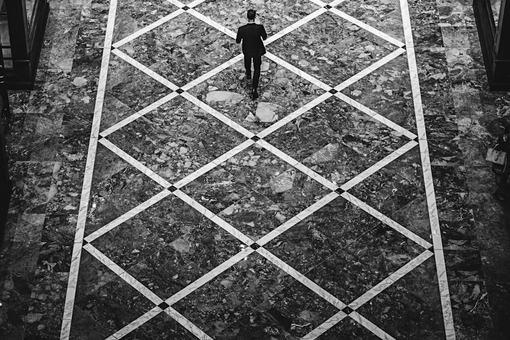 A male walking down a diamond-patterned street.